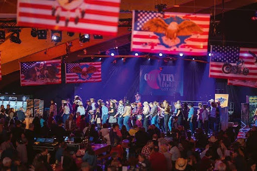 Line dancers on stage beneath American flags inside the Country Night Gstaad tent