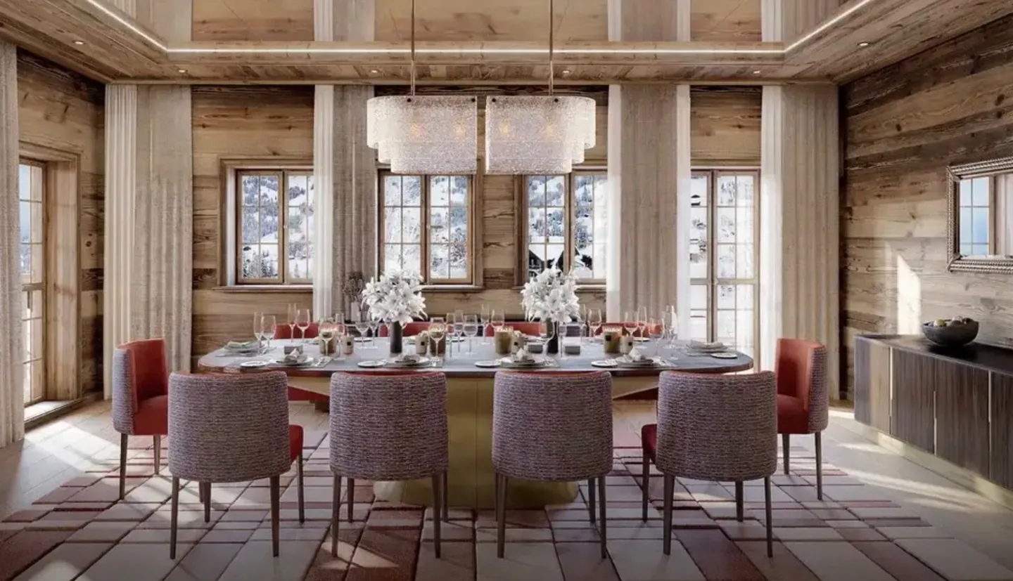 A chalet dining room laid for ten, with snow on the slopes visible through the windows