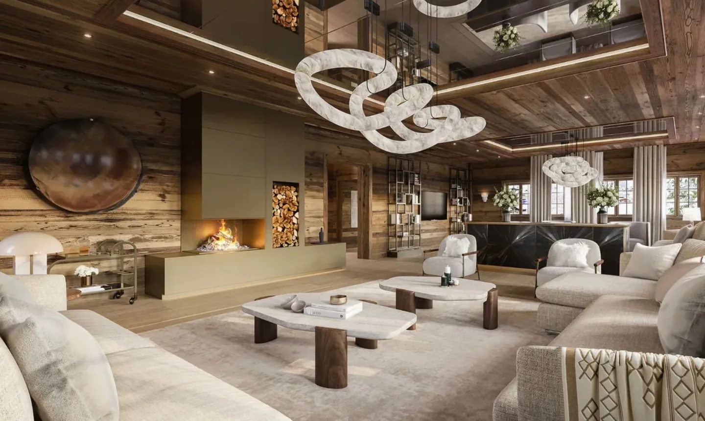 A chalet living room with a lit fire, alabaster light fittings and deep sofas beneath a timber ceiling